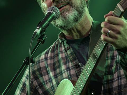 Close-up of vocalist singing with eyes closed under green stage light, Visualz photo
