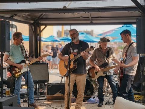 The Threads performing on a summer patio under a covered gazebo, blue umbrellas in background